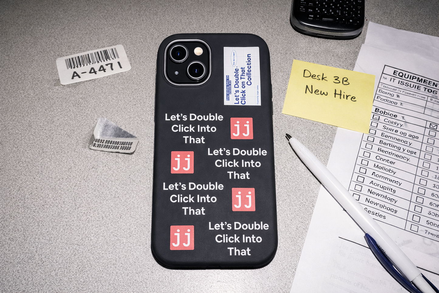 Jargon Junkie black iPhone 14 case with Let's Double Click Into That text and JJ logos on office desk with IT equipment issue log corporate humor phone accessory