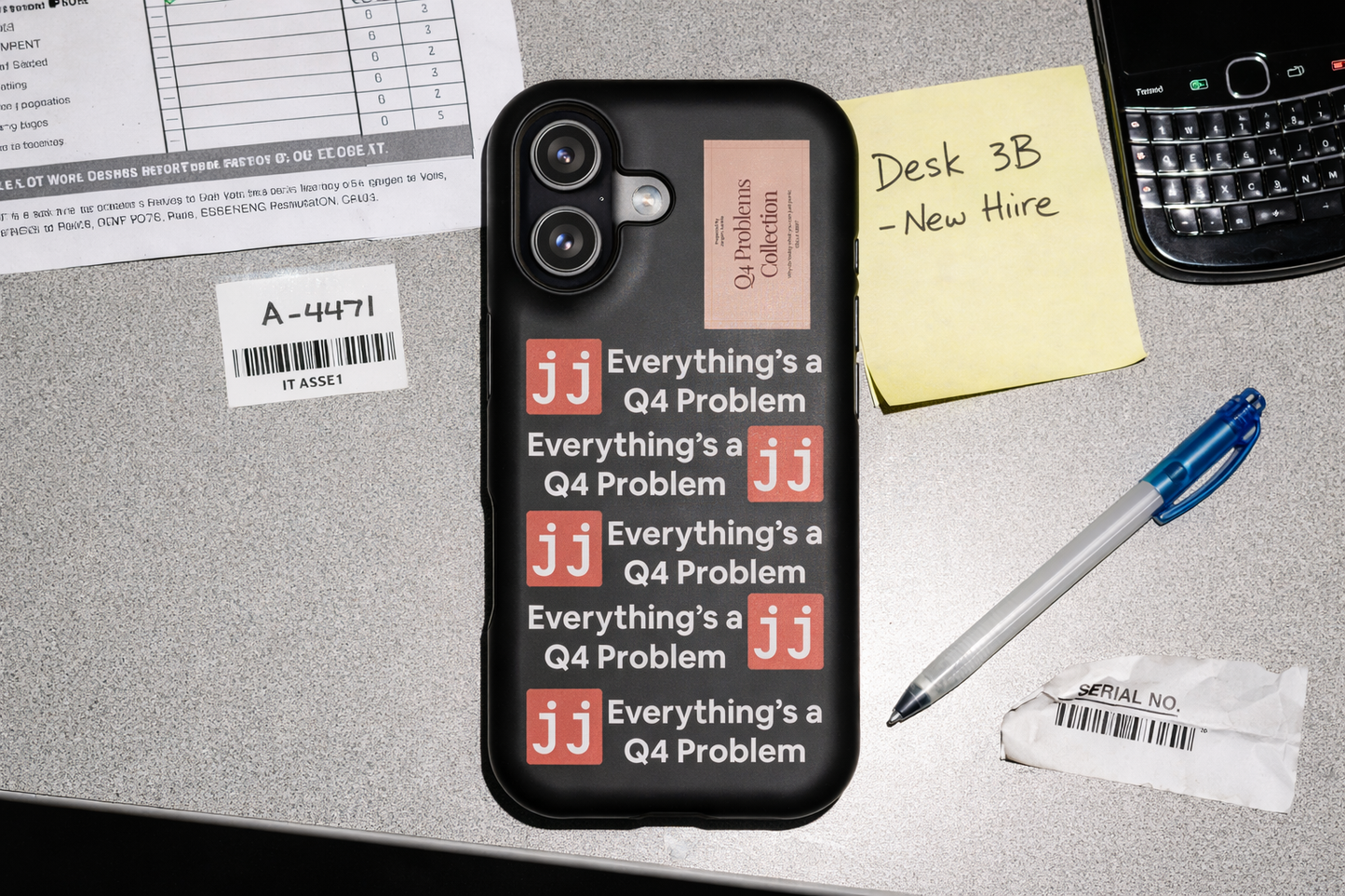 Everything’s a Q4 Problem' phone case on a desk with an equipment issue log, vintage BlackBerry, and New Hire note.