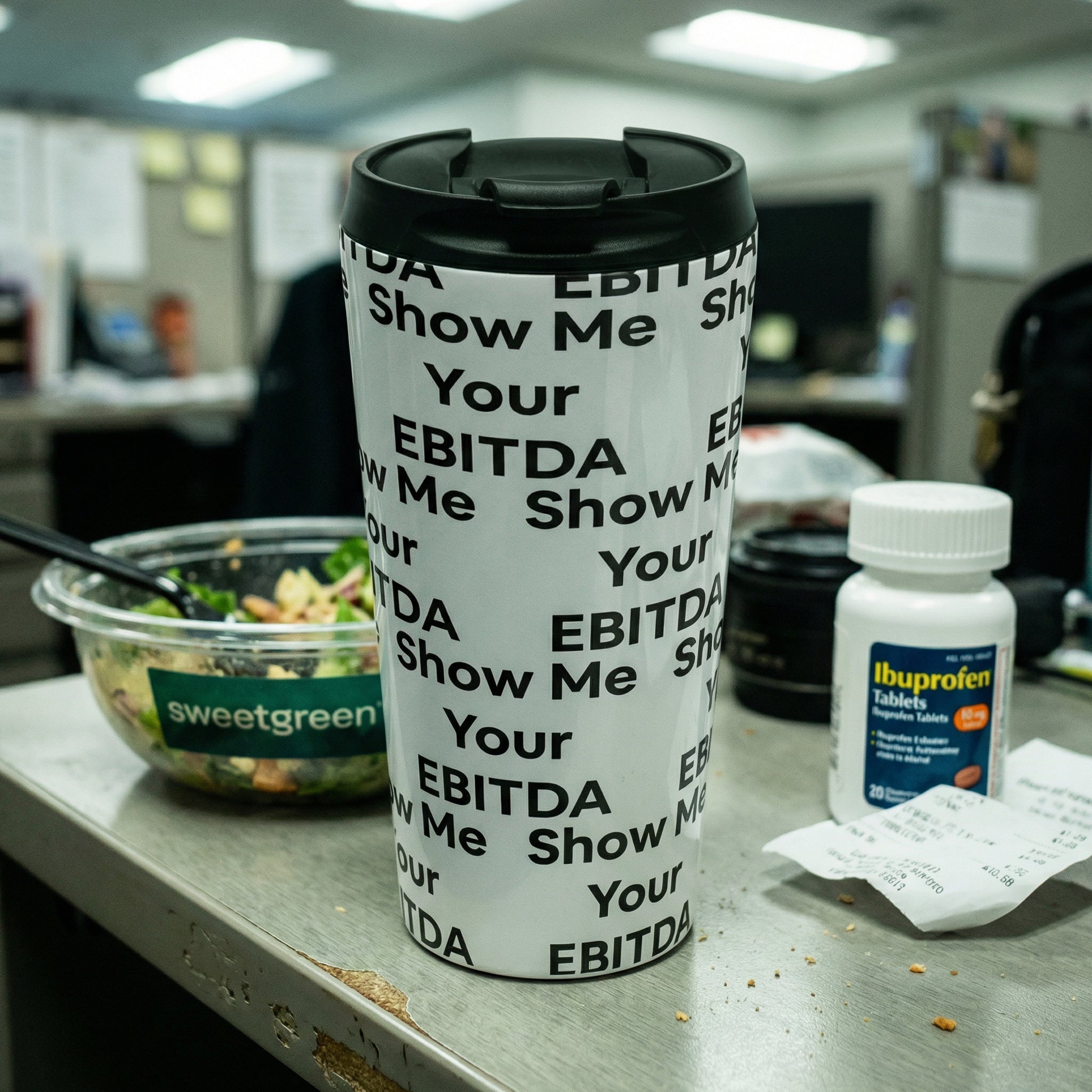 Jargon Junkie white tumbler with Show Me Your EBITDA text pattern on office desk lifestyle shot corporate humor drinkware